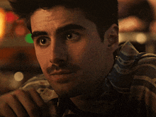 a close up of a man 's face with a mustache wearing a striped shirt