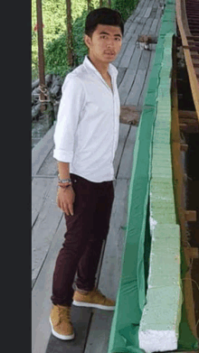 a man in a white shirt and maroon pants is standing next to a green wall
