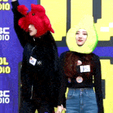 a woman wearing an avocado hat holds hands with another woman wearing a crab hat