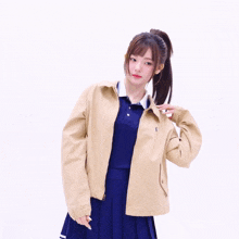 a girl with a ponytail is wearing a tan jacket and a blue polo shirt