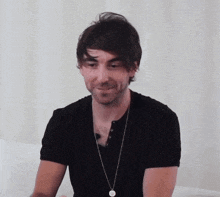 a man wearing a black shirt and a necklace with a circle on it