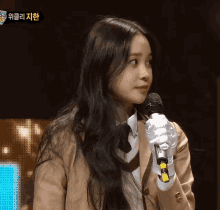 a girl with long hair is holding a microphone in front of a sign that says ' korean ' on it
