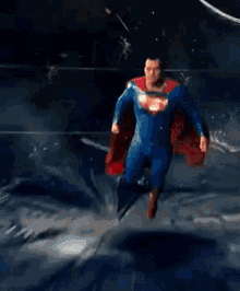 a man in a superman costume is standing with his arms outstretched in front of a building .