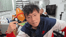 a man wearing glasses and a nike jacket holds a balloon in his hand