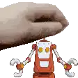 a hand is holding a toy robot on top of a white surface .