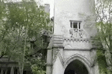 a black and white photo of a building with a balcony in the middle of a forest surrounded by trees .