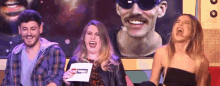 a group of people are laughing in front of a picture of a man with a mustache