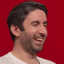a man with a beard and a white shirt is smiling with his eyes closed