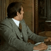 a man in a suit is sitting at a desk