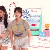 a couple of girls are standing next to each other in front of a drink machine .