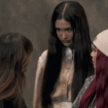 a woman with long hair is wearing a white beanie with the letter t on it