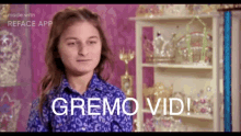 a girl in a blue shirt is standing in front of a shelf with trophies and the words gremo vid written on it .