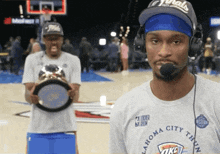 a man wearing a oklahoma city thunder t-shirt holds a trophy