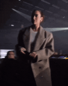 a woman is holding a microphone in her hand and giving a thumbs up