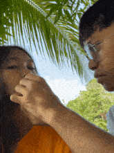 a man touches a woman 's nose under a palm tree leaf