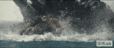 a giant monster is coming out of the ocean in a gif .