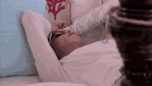 a woman is laying in bed with her head on a pillow and sunglasses on .