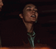 a woman is holding a candle in her hand in a dark room with her eyes closed .