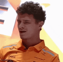 a man wearing an orange shirt with the word dell on it is making a funny face .