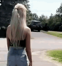 a woman in shorts and a black tank top is walking down the street .