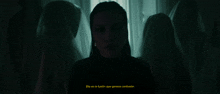 a group of ghosts are standing around a woman in the dark .