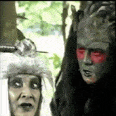 a man and a woman are standing next to each other with their faces painted in different colors .