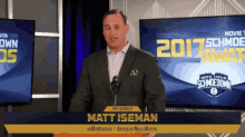 matt iseman stands at a podium in front of a screen that says 2017 schmoe award
