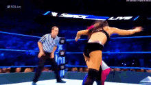 a woman in a wrestling ring with a referee standing behind her