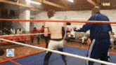 a man in a blue jacket is standing in a boxing ring with a sign that says aspa on it