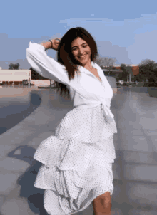 a woman wearing a white dress with polka dots is dancing