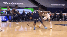 two basketball players are playing a game of basketball on a court with a crowd watching .