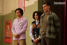 three people standing next to each other in front of an entertainment first look poster