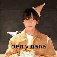 a man wearing a party hat is holding a cake with a candle .