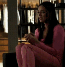 a woman in a pink shirt and pink pants is sitting on the floor