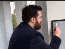 a man with a beard is writing on a whiteboard with a marker