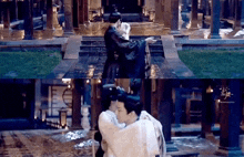 a man is carrying a woman in his arms in the rain in a building .