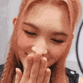 a close up of a woman covering her mouth with her hands .