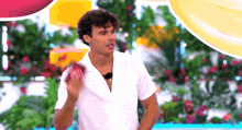 a man in a white shirt stands in front of flowers