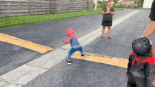 a little boy in a spiderman costume is walking across a street