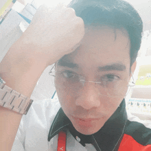 a man wearing glasses holds his hand to his forehead