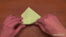 a person folding a piece of green paper with the words made in animotica visible