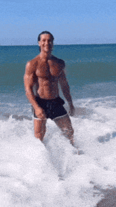 a shirtless man is standing in the water on a beach