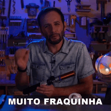 a man in a denim shirt is holding a torch and says " muito fraquinha "