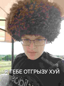 a man wearing glasses and a large afro wig
