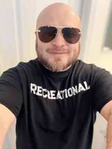 a bald man wearing sunglasses and a black recreational shirt
