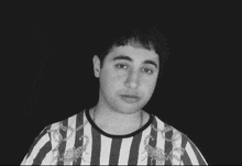 a black and white photo of a young man wearing a striped shirt with chains on it