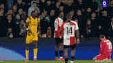 a soccer player with the number 14 on his jersey stands on the field