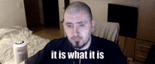 a man with a beard says it is what it is in front of a white fan