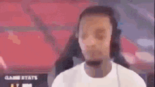 a man wearing headphones and a white shirt is talking on a video call .