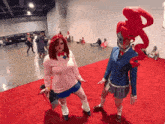 a woman in a pink sweater is standing next to a woman in a blue suit on a red carpet